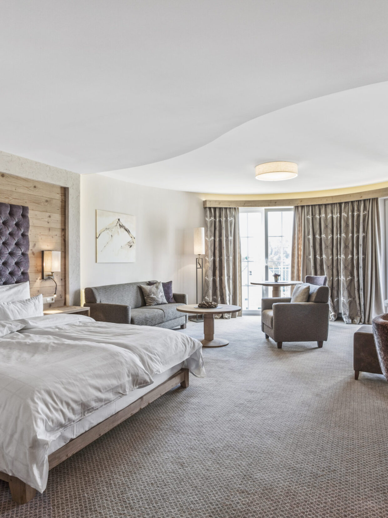 Spacious hotel room with a double bed and a seating area.