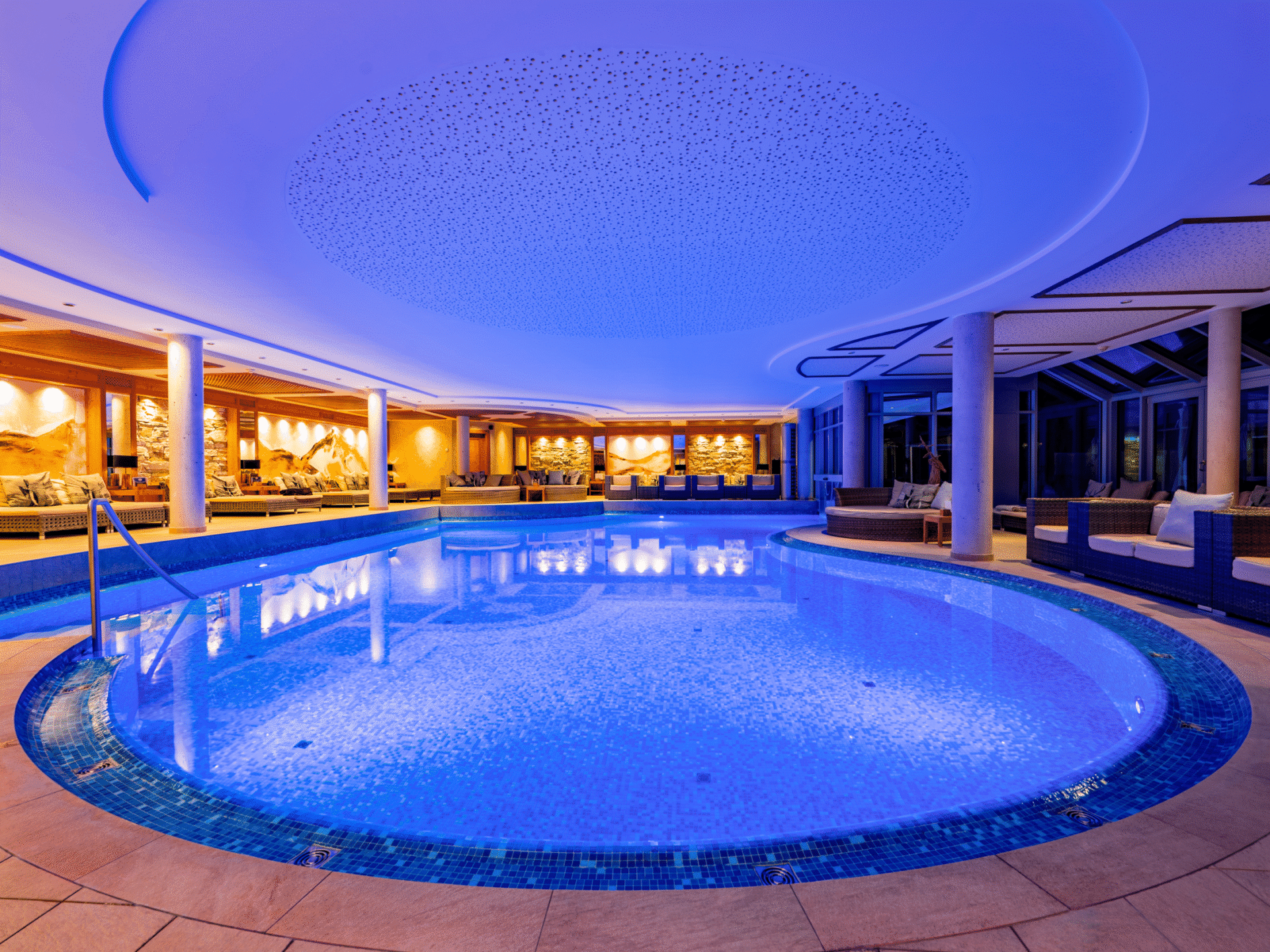 Beleuchteter Innenpool im 2000m² SPA Bereich im Meiser SPA Resort mit Liegebereich und alpiner Wandgestaltung