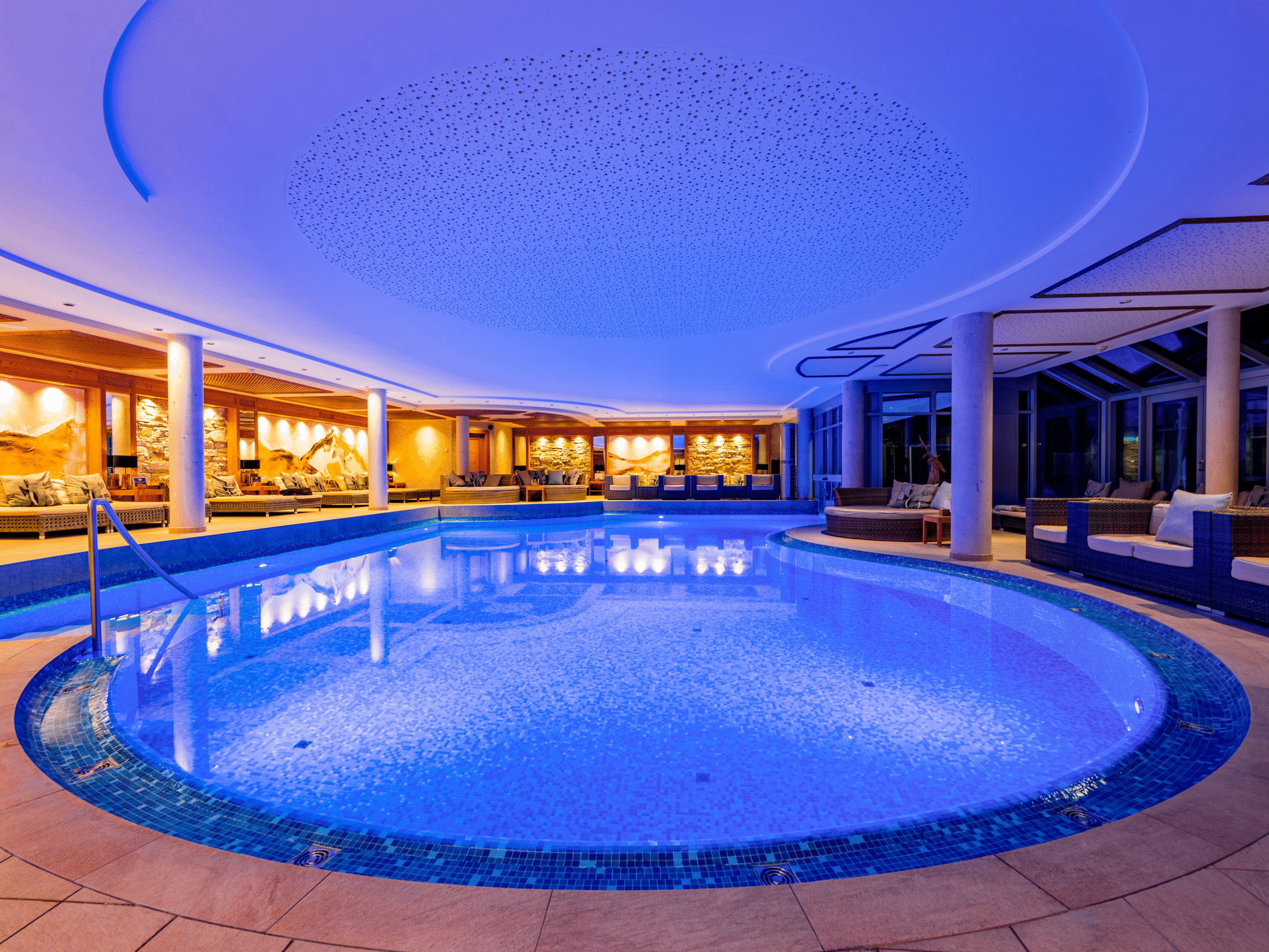 Illuminated indoor pool in the 2000m² SPA area in the Meiser SPA Resort with sunbathing area and alpine wall design