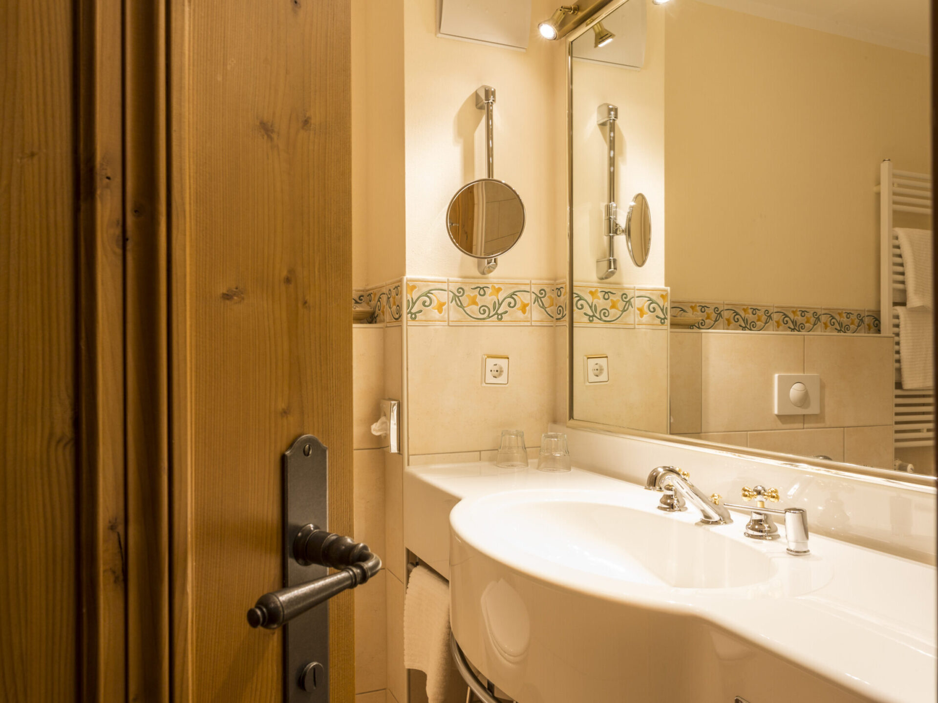Wash area with large mirror, light-colored tiles and playful border in the Comfort room country house with balcony