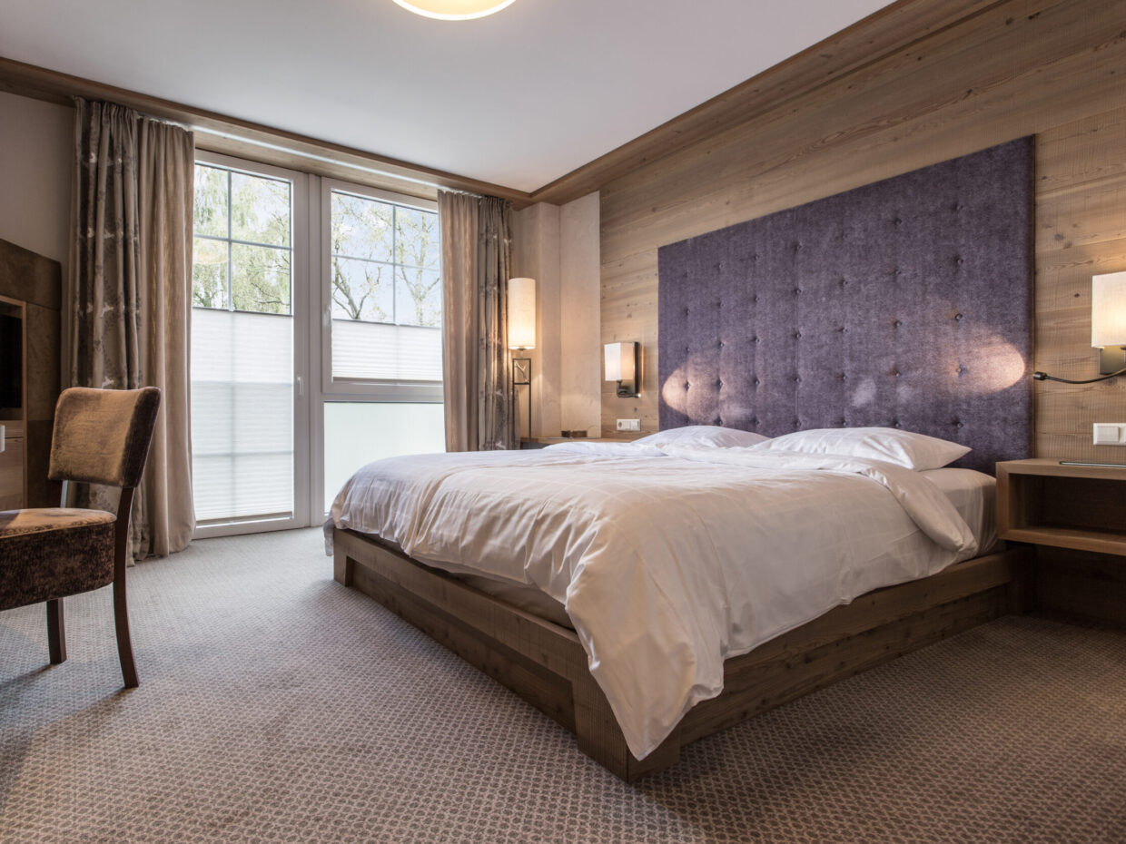 Modern hotel room with double bed and desk.