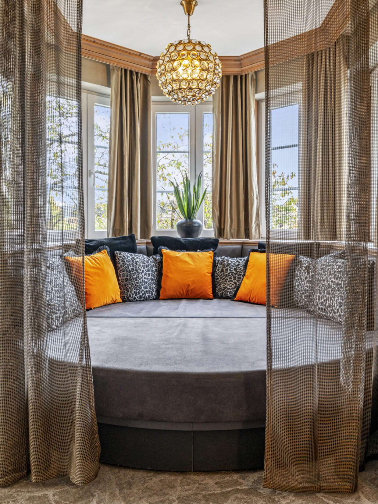 Comfortable seating area with orange cushions and a plant.