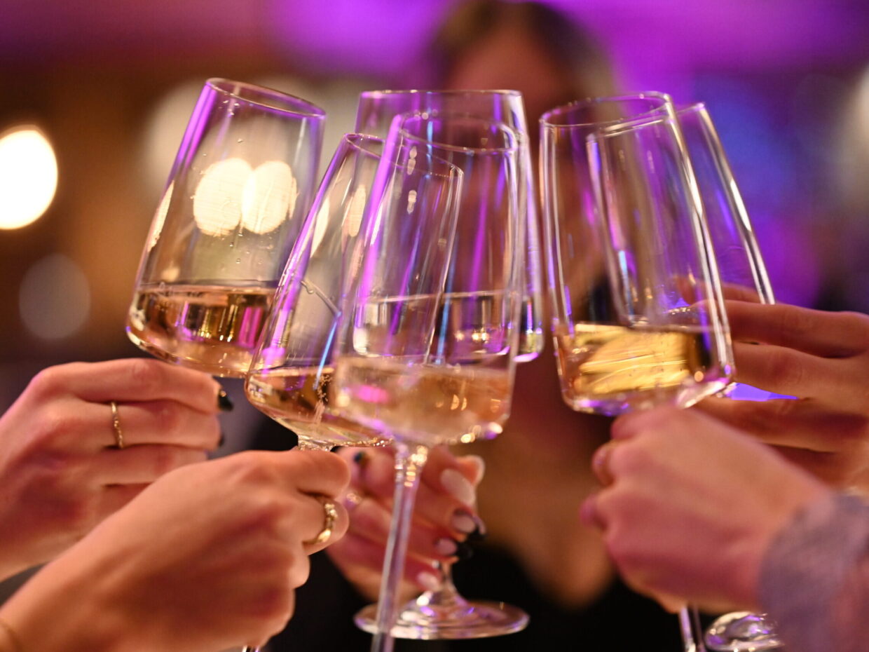 Menschen stoßen mit Sektgläsern an, Feierabendstimmung.