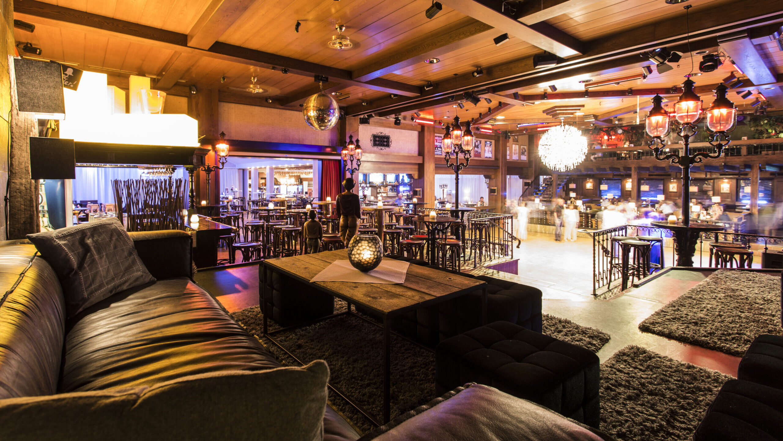 Gemütlicher Club mit Bar und Sitzbereich, warm beleuchtet.