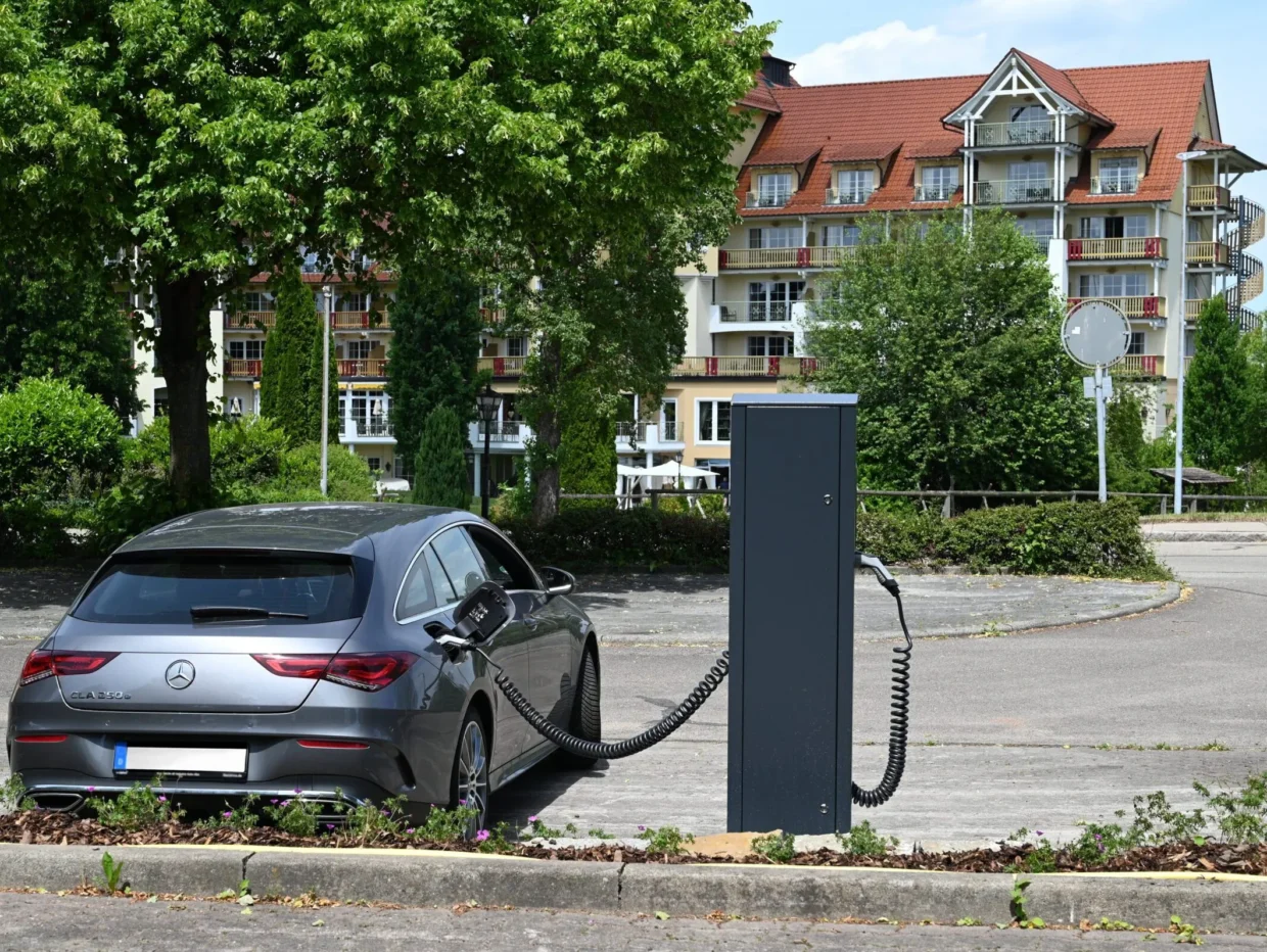 Elektroauto lädt an Ladestation vor Wohngebäude.