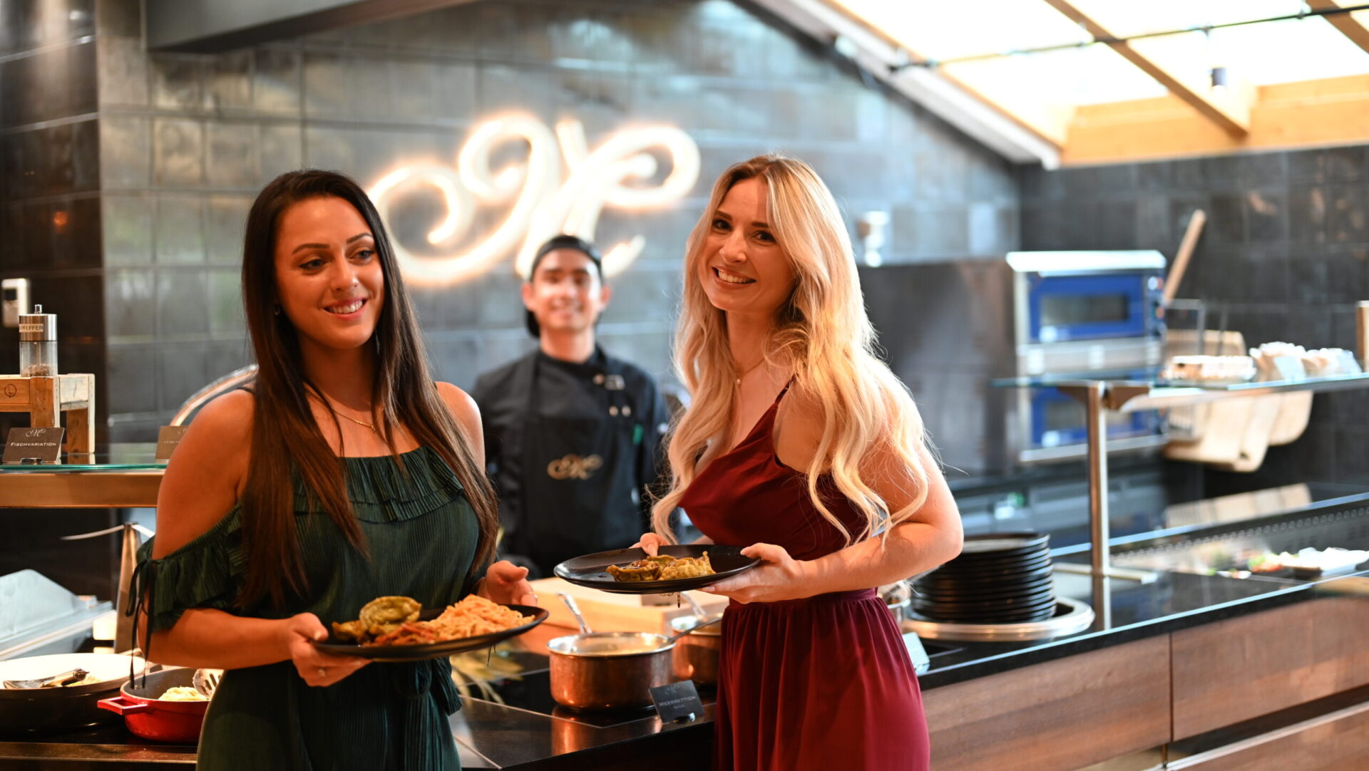 Two women smiling with plates in a restaurant.