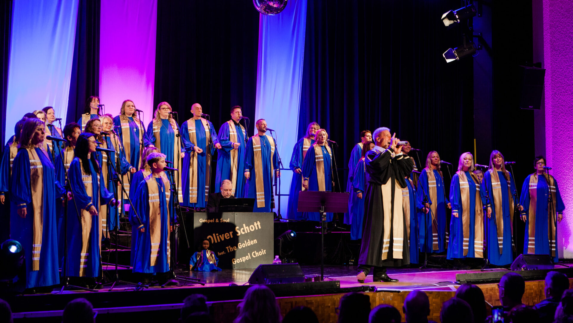 Gospelchor singt auf Bühne mit buntem Licht
