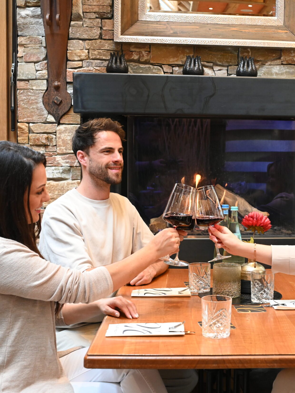 Drei Personen stoßen mit Rotwein an, Restaurantambiente