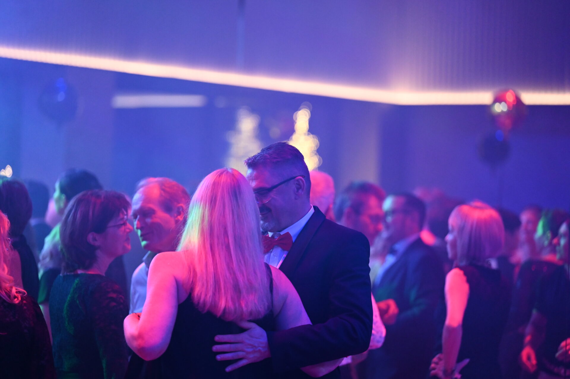 People dance at a party in festive lighting in the Meiser Congress Plaza.