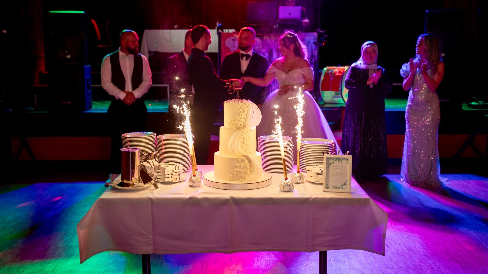 Hochzeitspaar mit Hochzeitstorte und Gästen