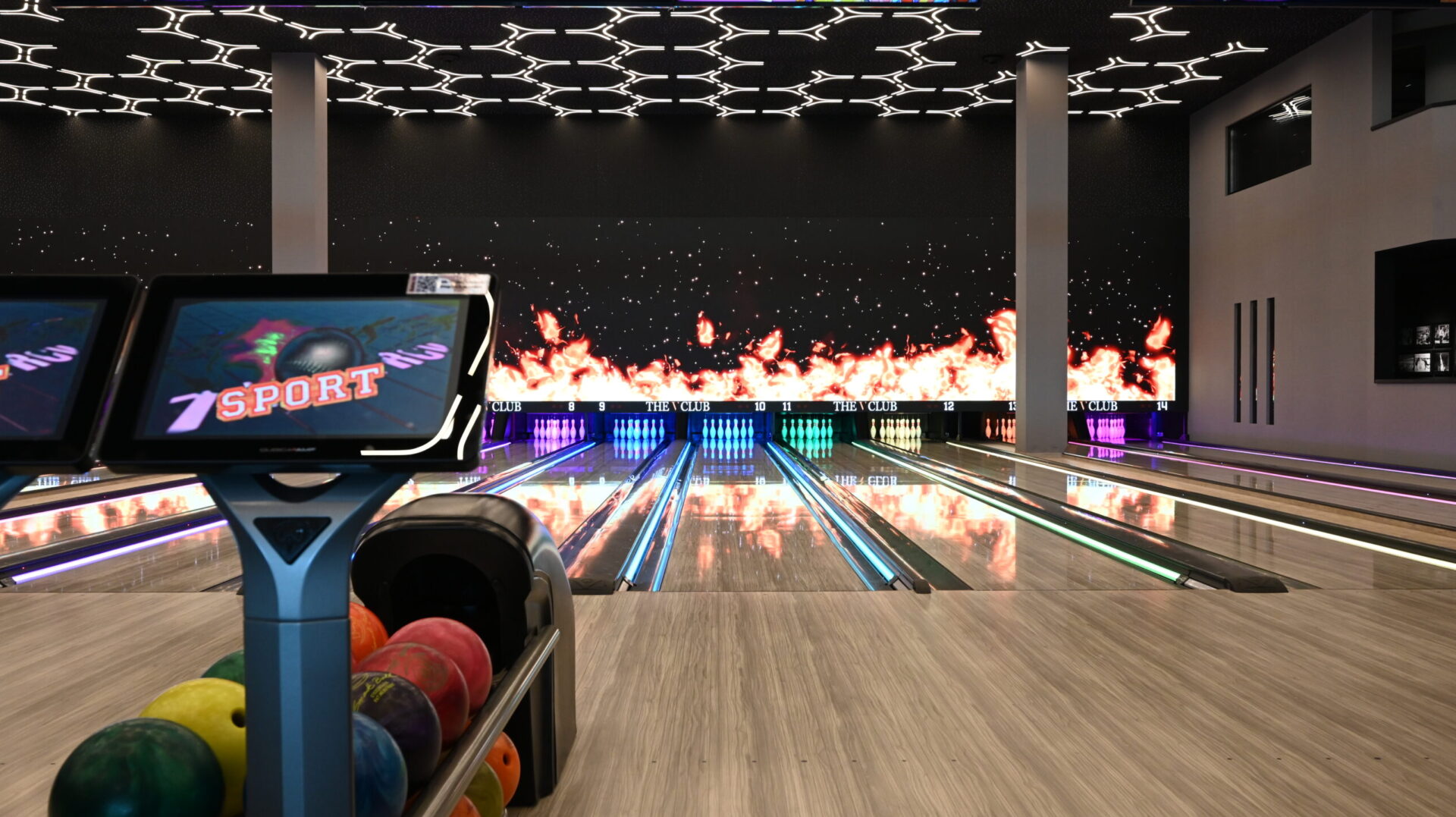 Neonbeleuchtete Bowlingbahn mit bunten Kugeln und Bildschirmen