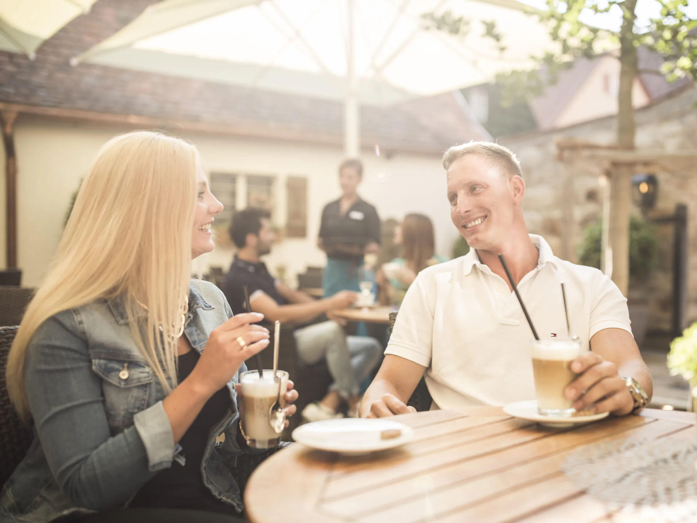 Personen genießen Kaffee bei Sonnenschein im Freien