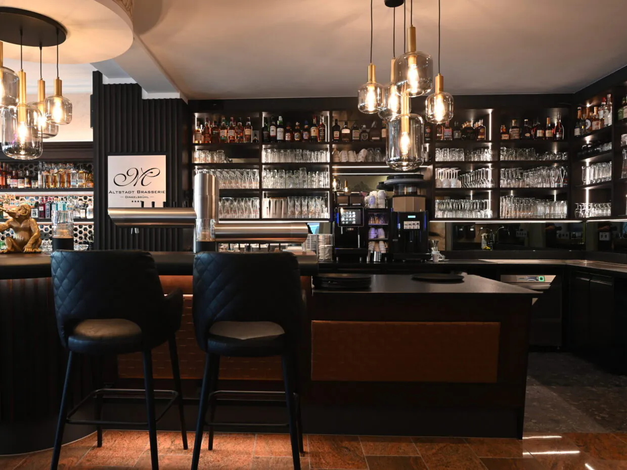 Elegante Bar mit moderner Beleuchtung und Gläserregalen.