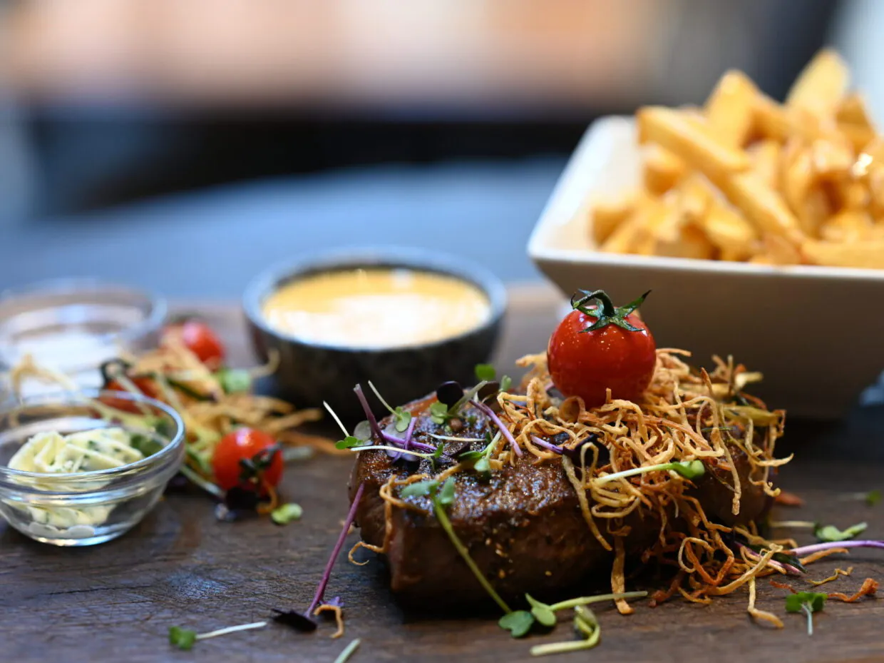 Gourmet-Steak mit Pommes, Beilagen und Sauce serviert.