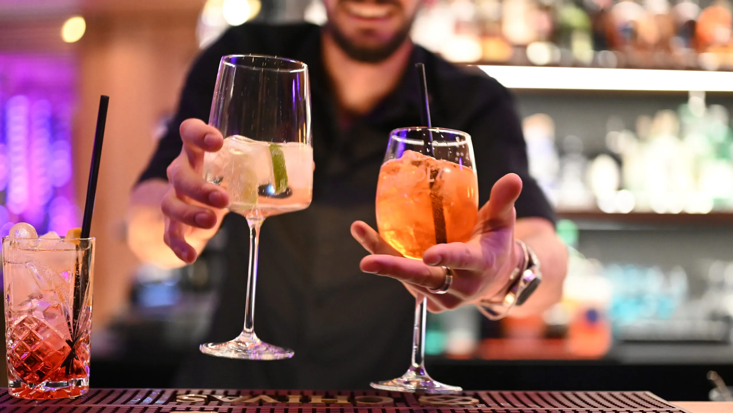 Barkeeper serviert bunte Cocktails in einer Bar