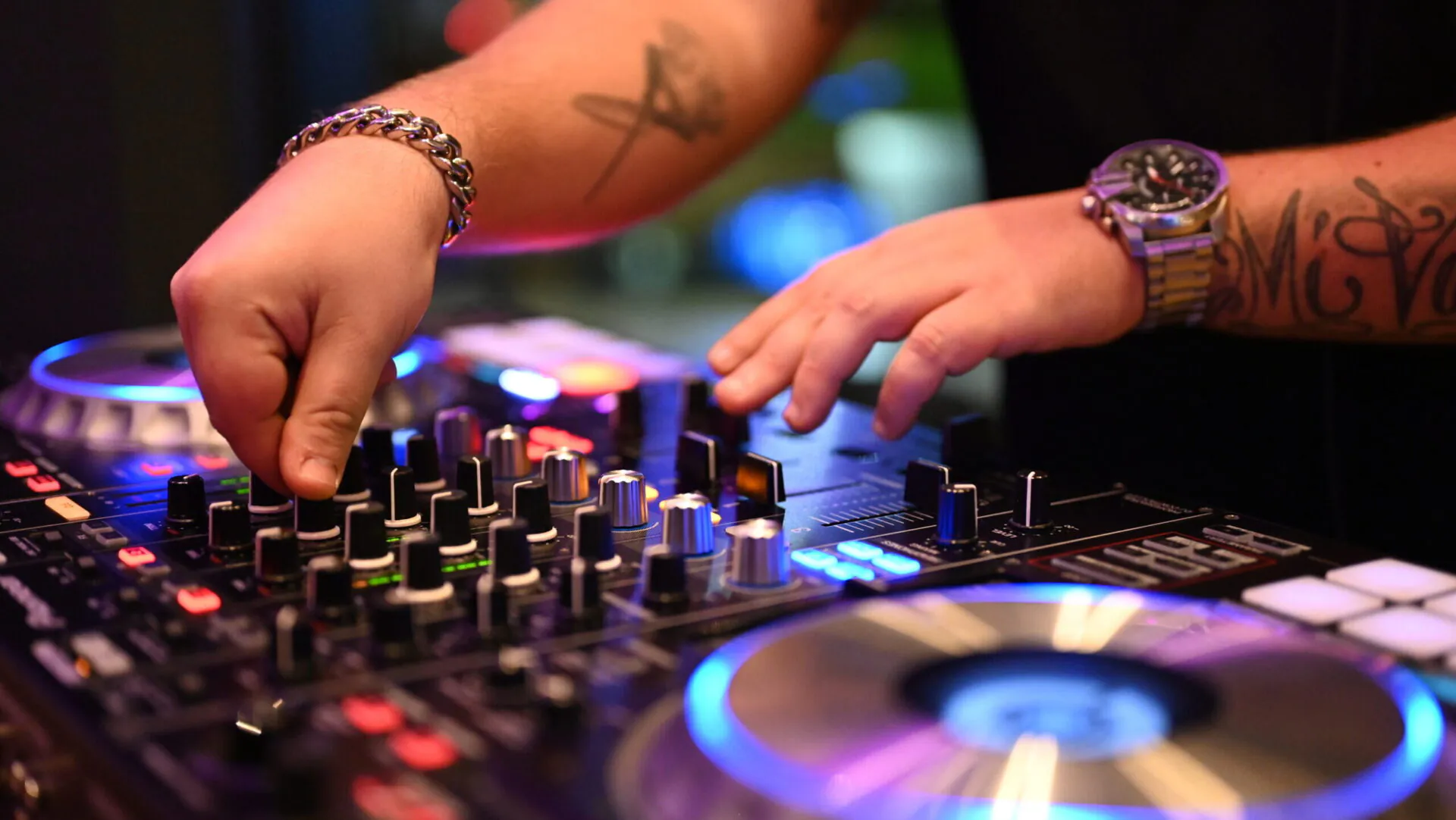 DJ mischt Musik auf Konsole mit Lichteffekten.