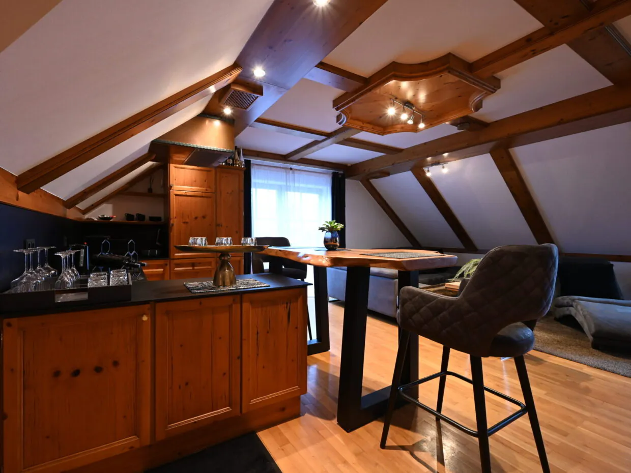 Gemütliche Dachgeschoss-Wohnung mit Holzmöbeln und Barhocker.