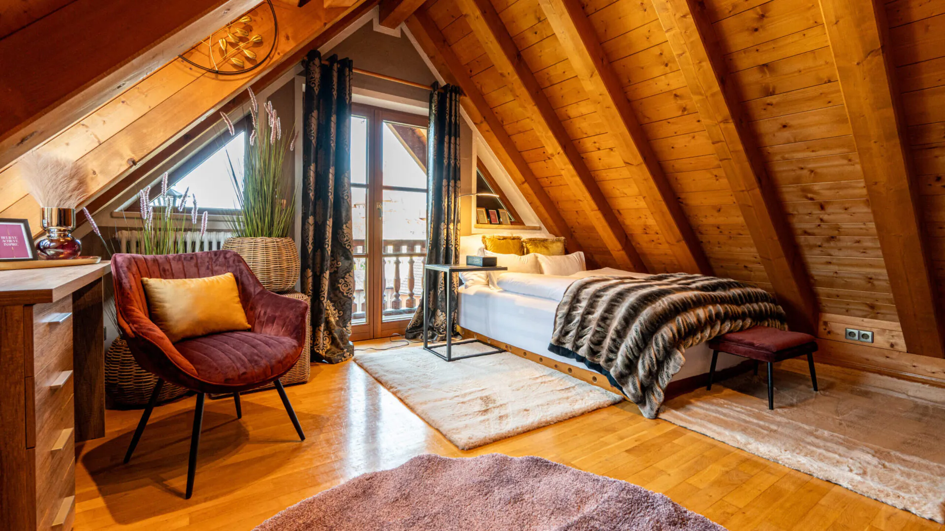 Gemütliches Dachzimmer mit Bett und Sessel.