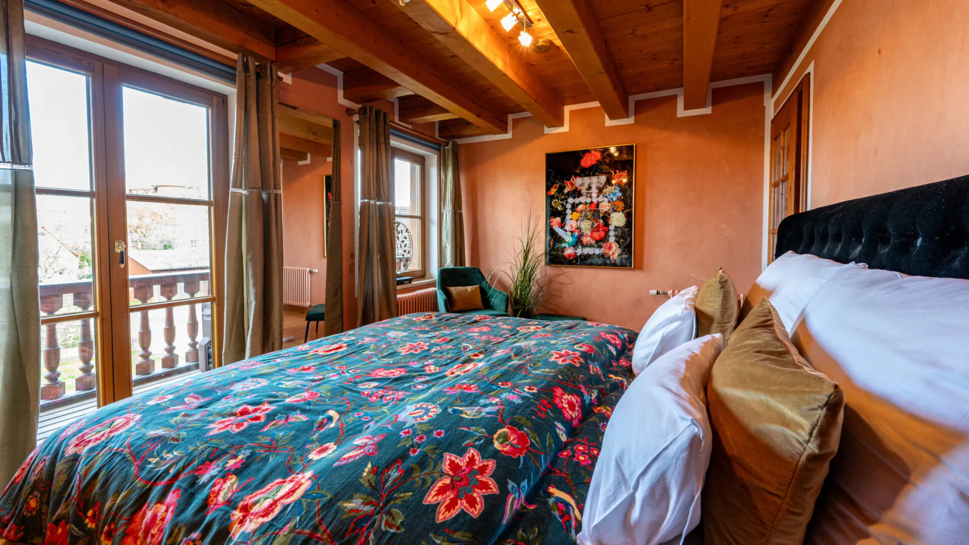 Gemütliches Schlafzimmer mit Blumenbettwäsche und Holzbalkendecke.