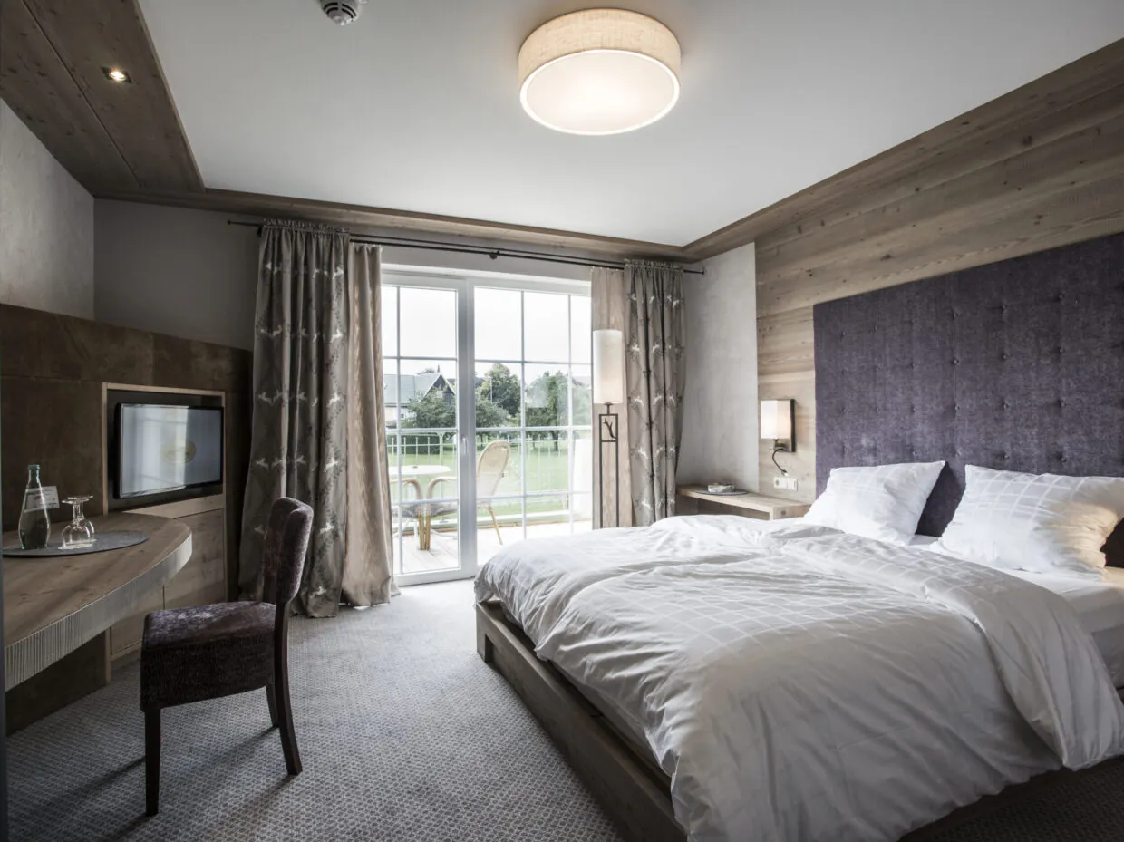 Comfort-Zimmer im alpinen Stil mit Doppelbett, Balkon und Blick auf die Natur im Meiser SPA Resort nahe Dinkelsbühl