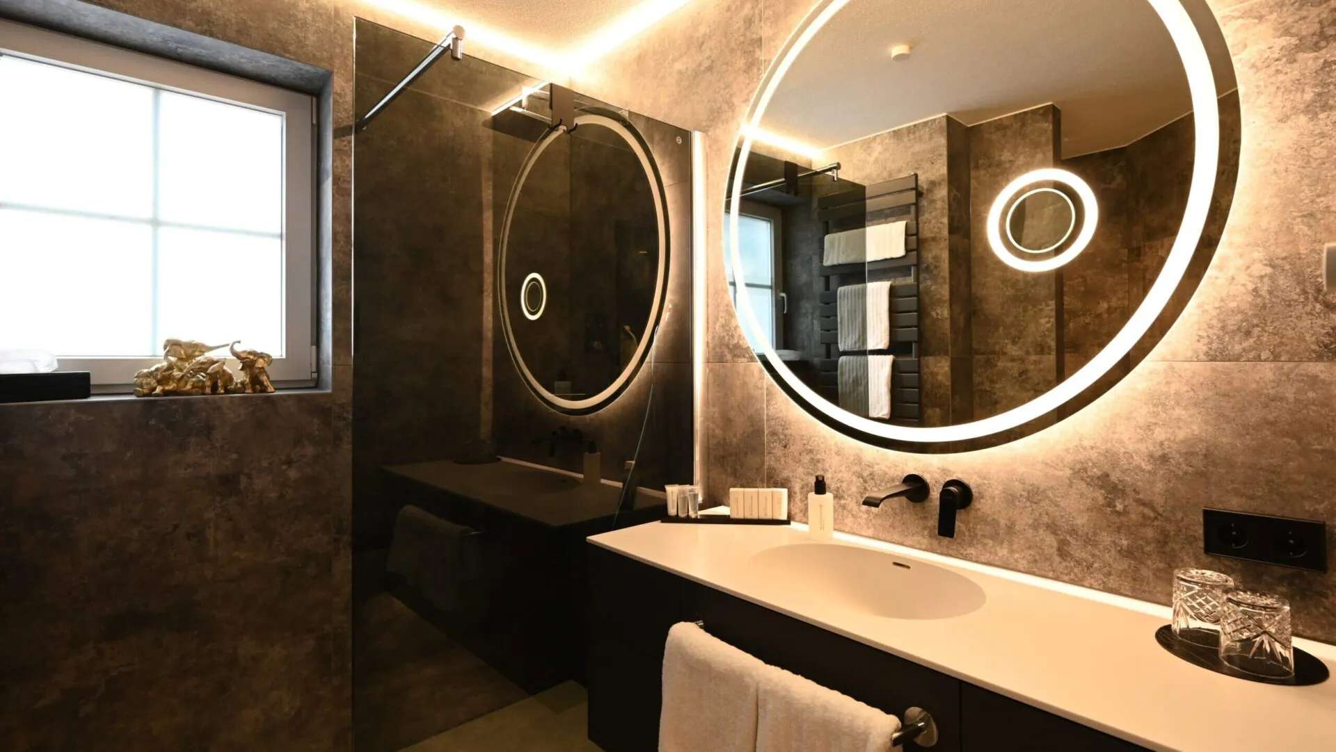 Modernes Badezimmer mit beleuchtetem Rundspiegel und Waschtisch