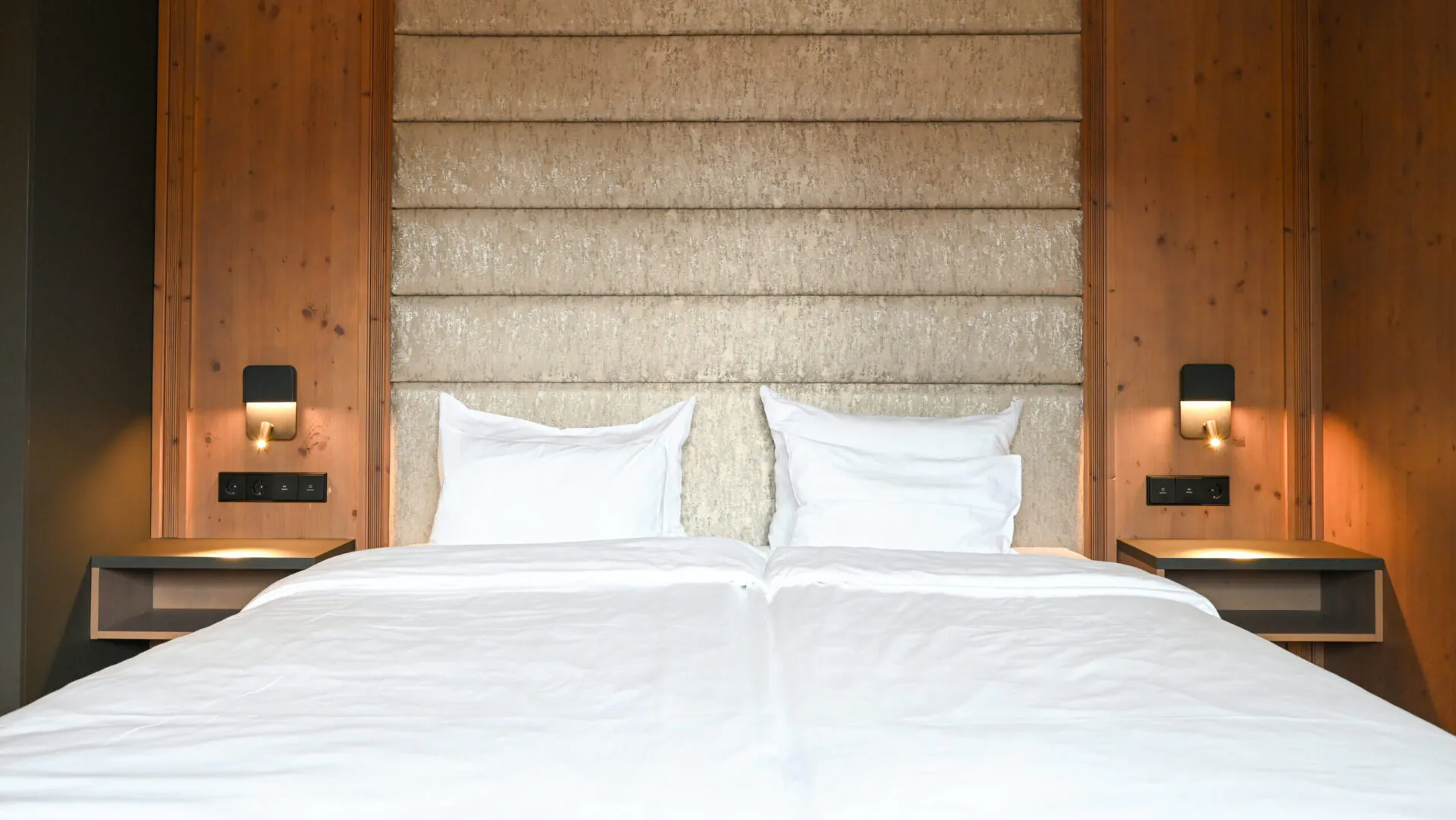 Moderner Hotelbettaufbau mit doppelten Kopfkissen, Holzwandlampen