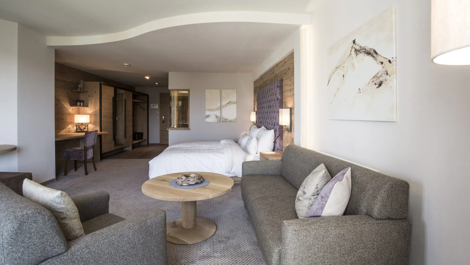 Modernes Hotelzimmer mit gemütlichem Sofa und Doppelbett.