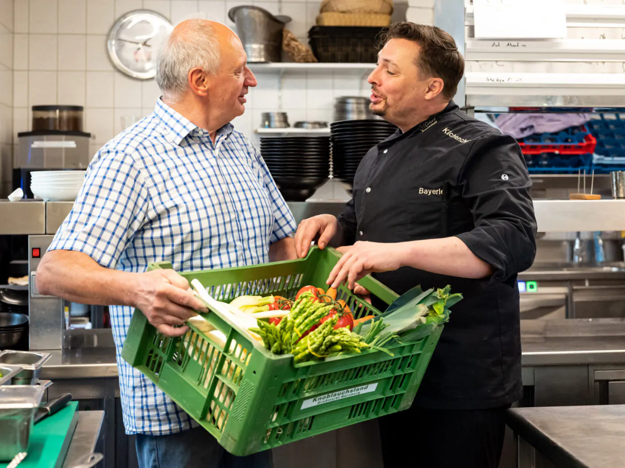 Mann und Koch mit Gemüsekiste in der Küche