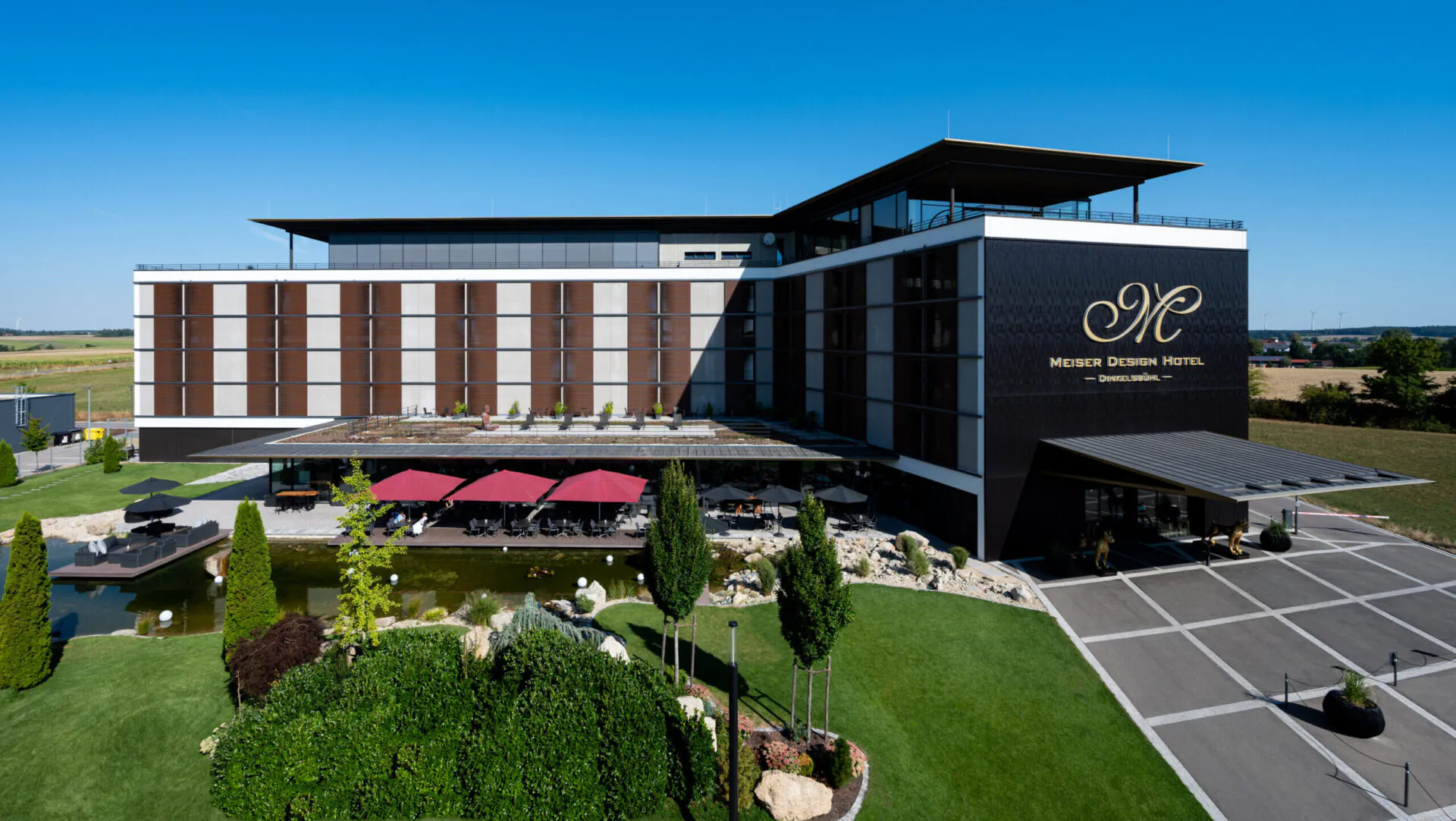 Modernes Hotelgebäude mit Gartenansicht und Terrasse.