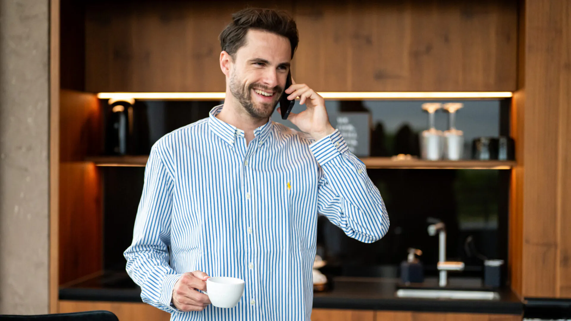 Mann telefoniert lächelnd mit einer Tasse Kaffee