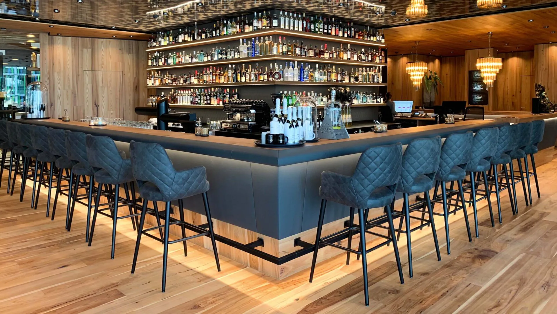 Moderne Bar mit hoher Bestuhlung und Regal mit Flaschen.