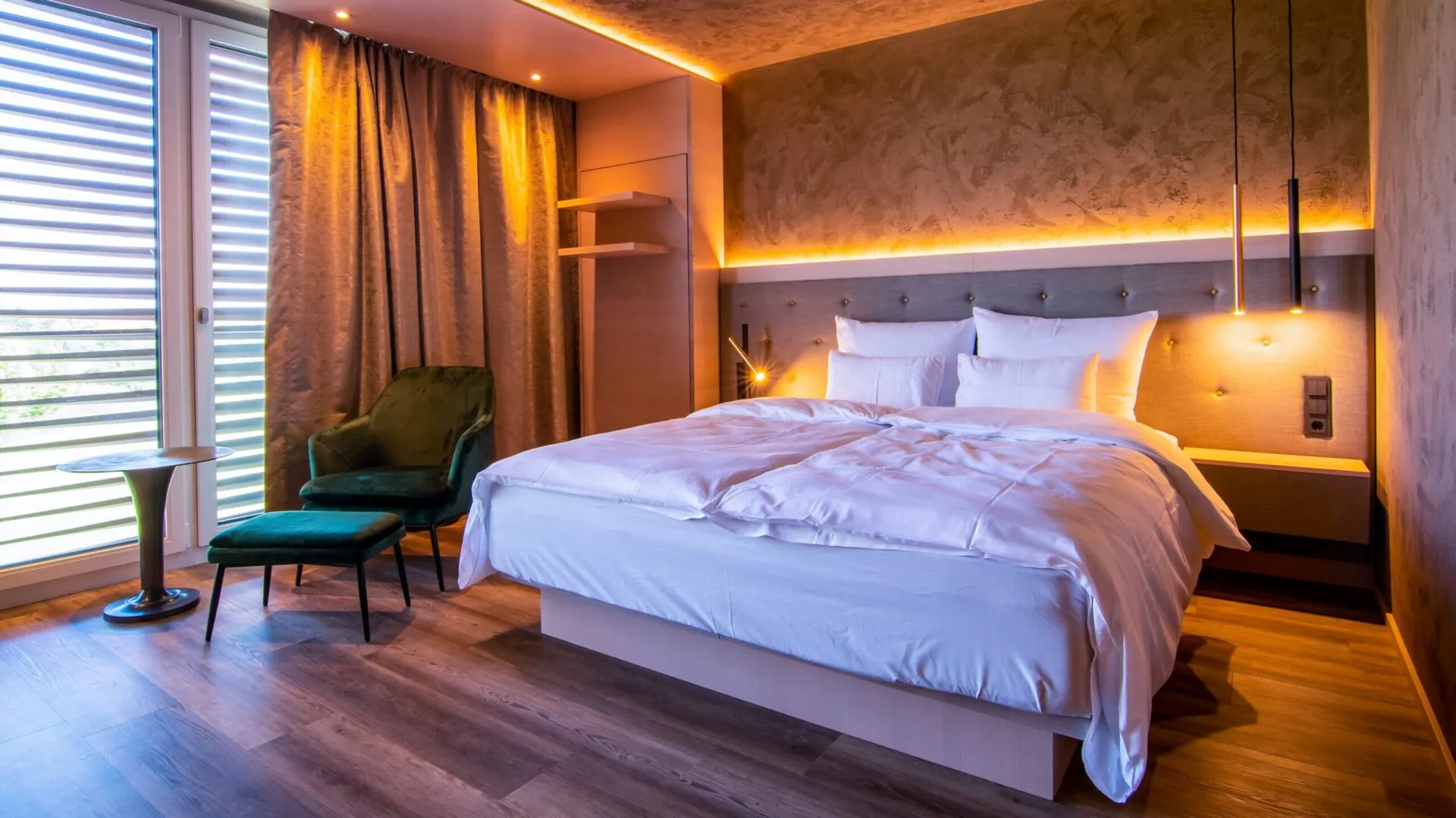 Modernes Hotelzimmer mit Doppelbett und grüner Sitzecke