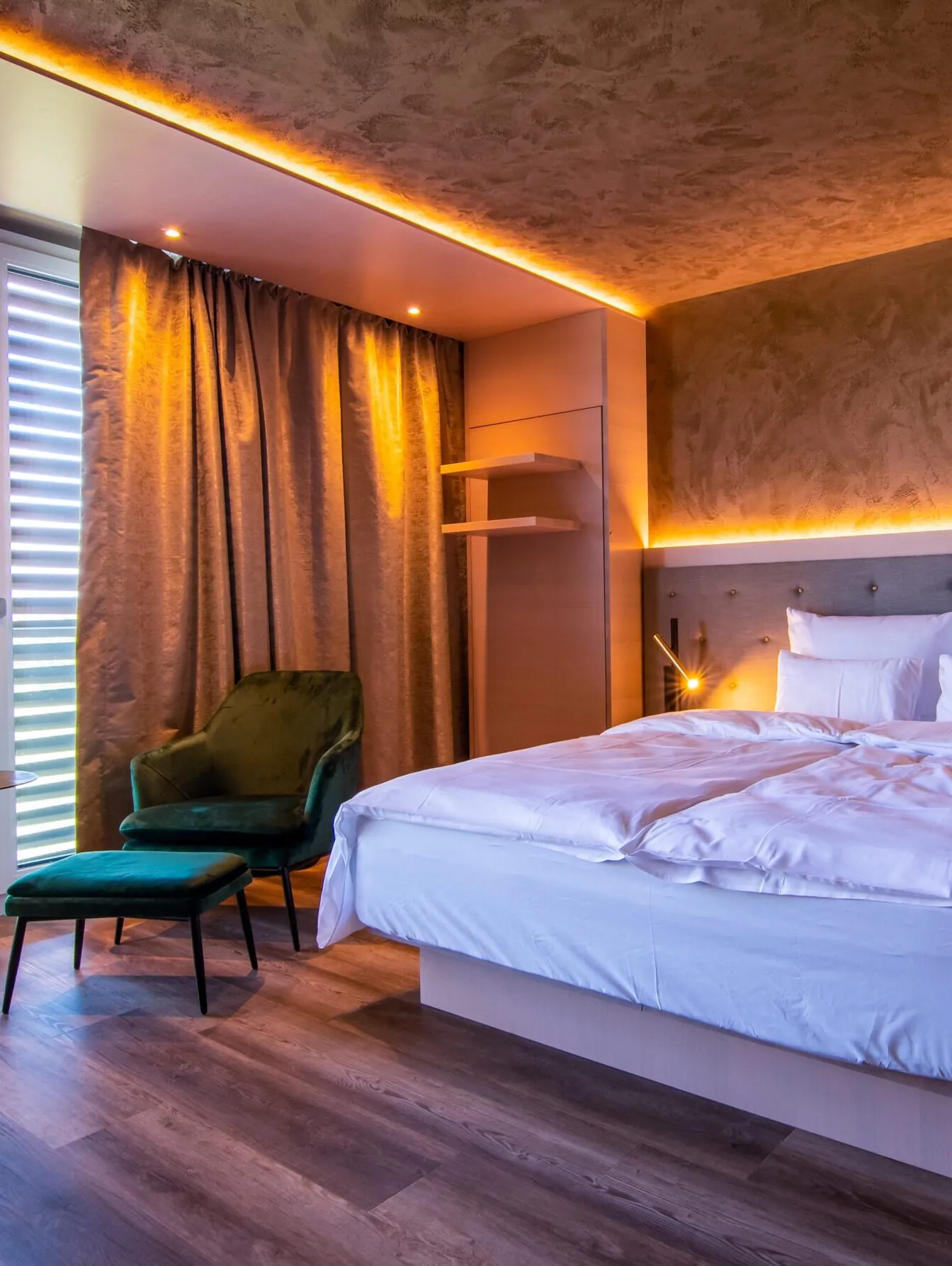 Modernes Hotelzimmer mit Doppelbett und grüner Sitzecke