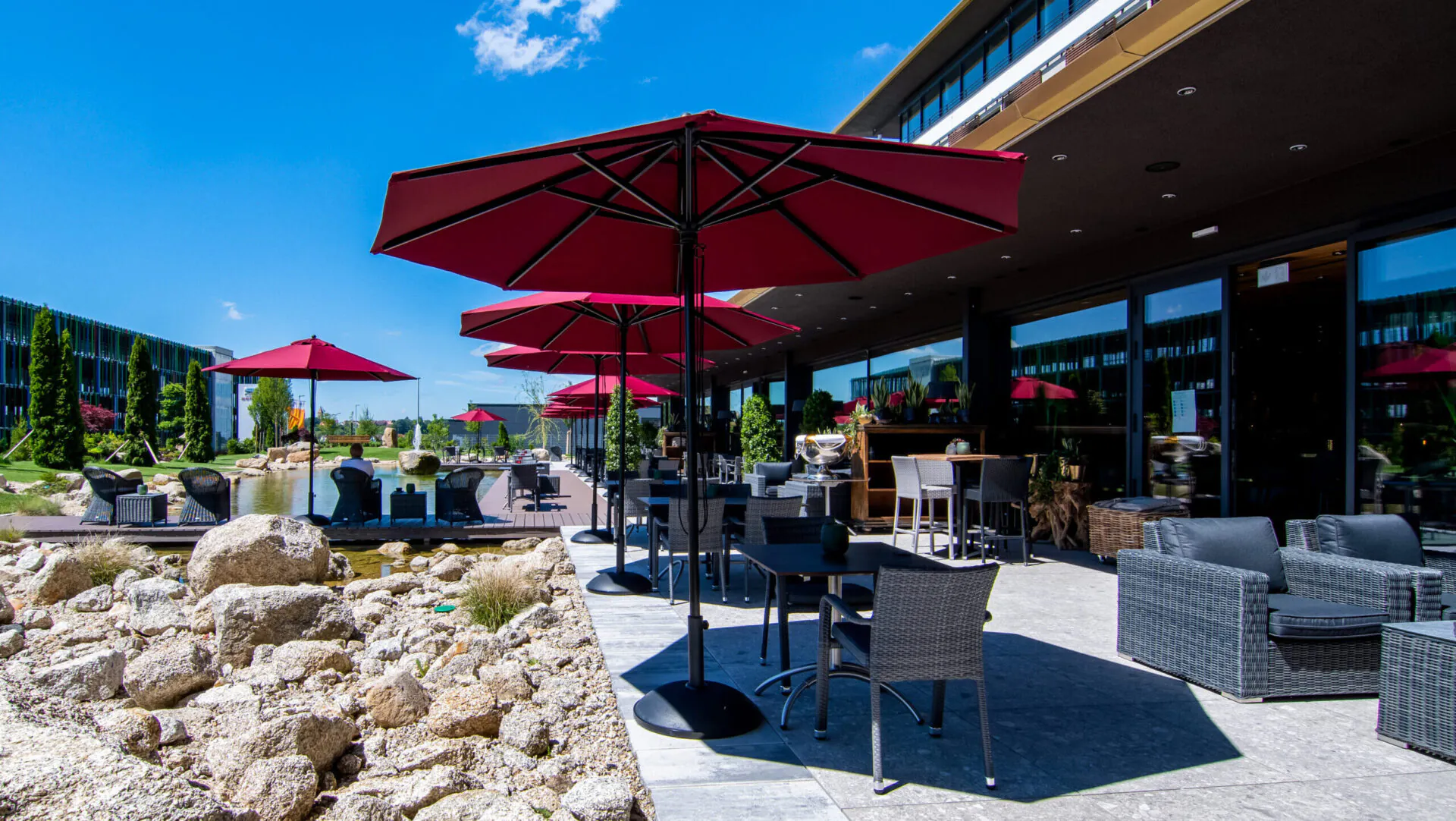 Garten Terrasse mit roten Sonnenschirmen und Stühlen.