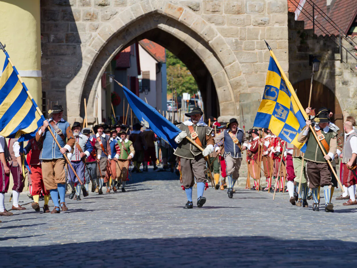 Historische Parade in traditionellen Kostümen und Fahnen.
