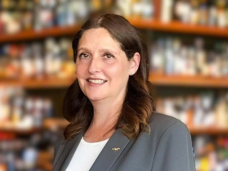 Frau vor Regal mit unscharfen Büchern, lächelnd