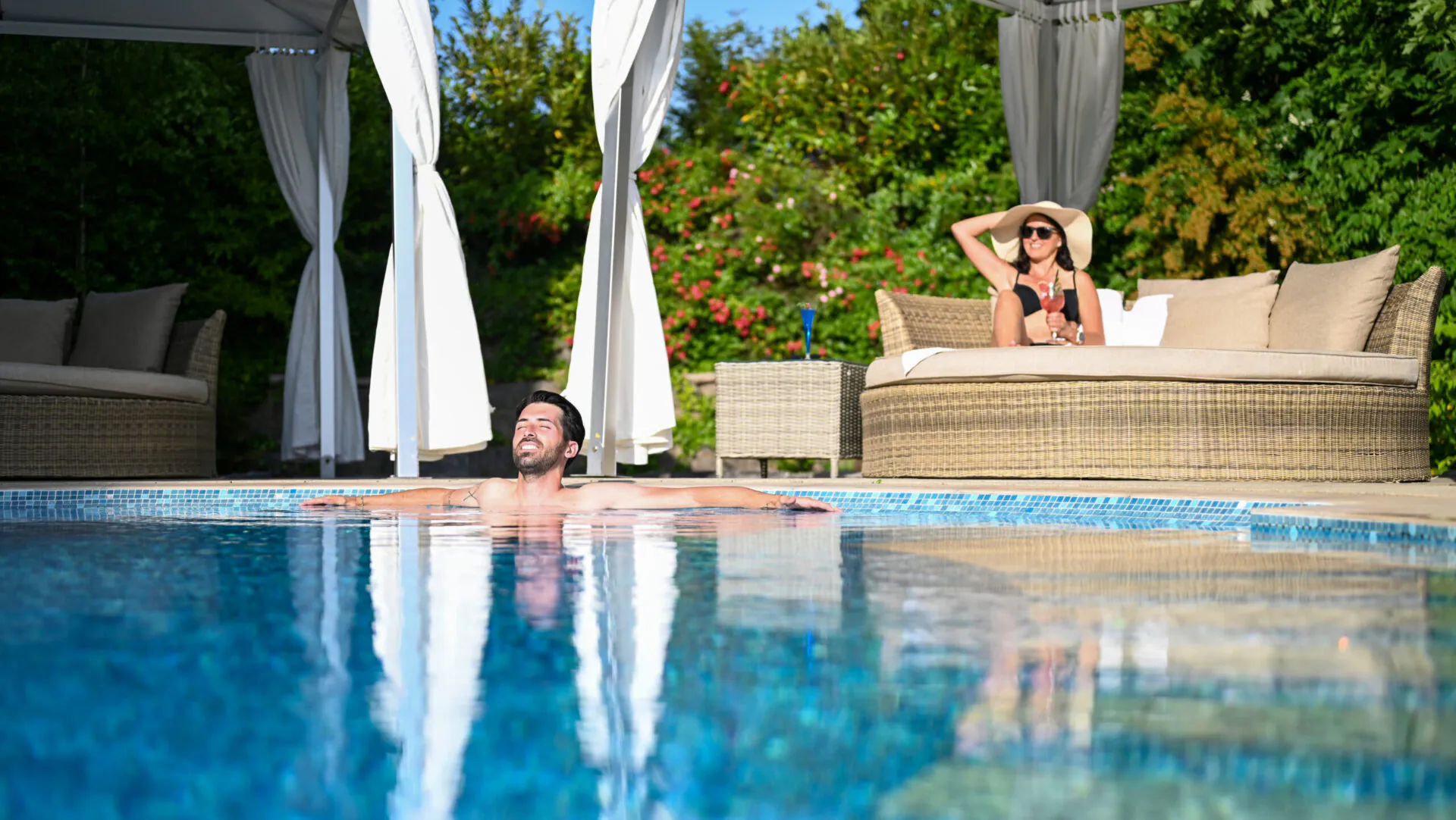 Entspannte Menschen am Pool unter Sonnenschirm