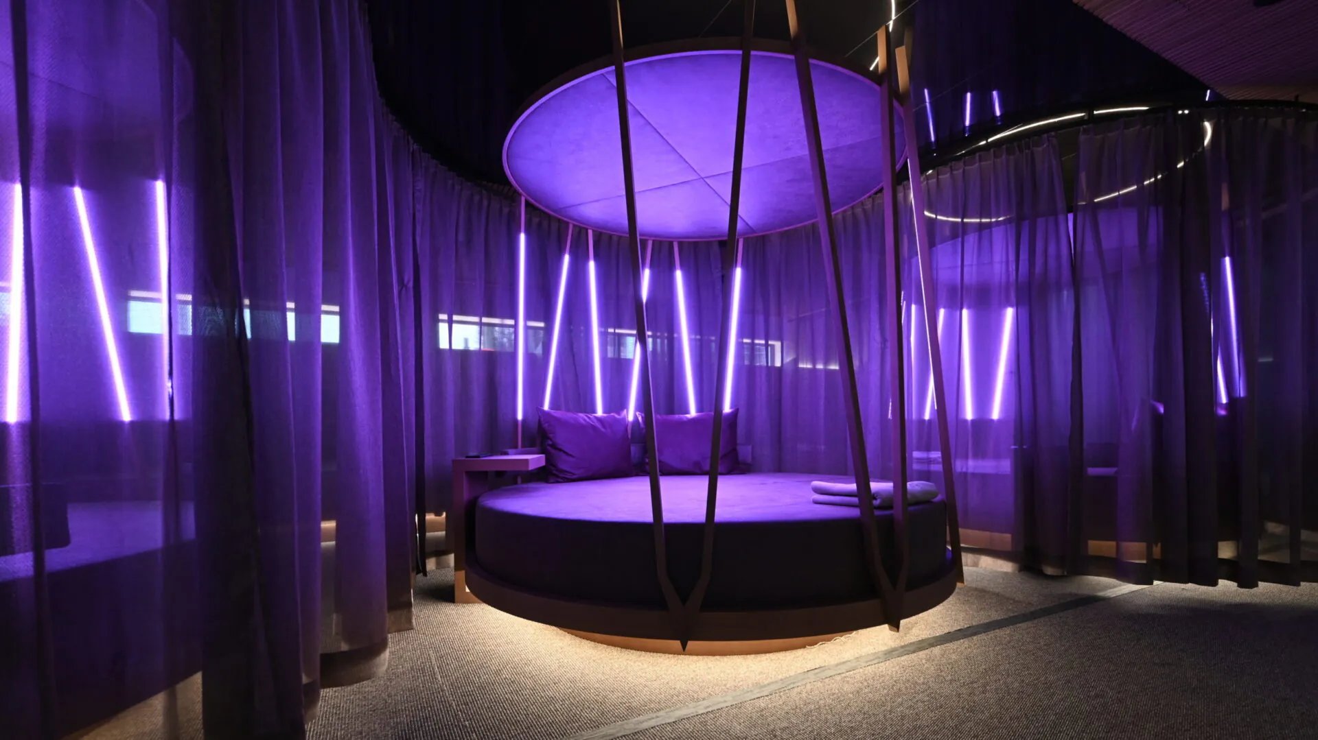 Violette Lounge mit runden Bett und Vorhängen