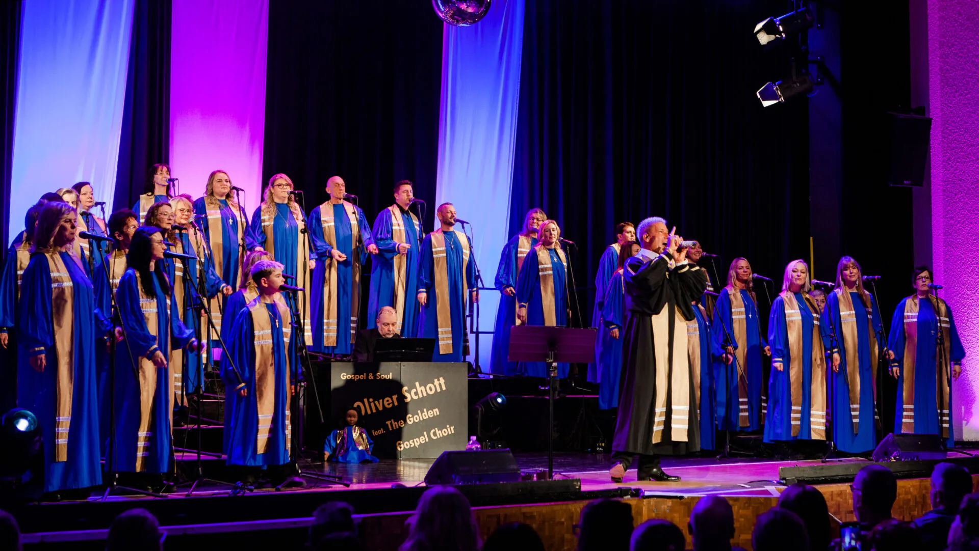 Gospelchor singt live auf der Bühne in blauen Roben.