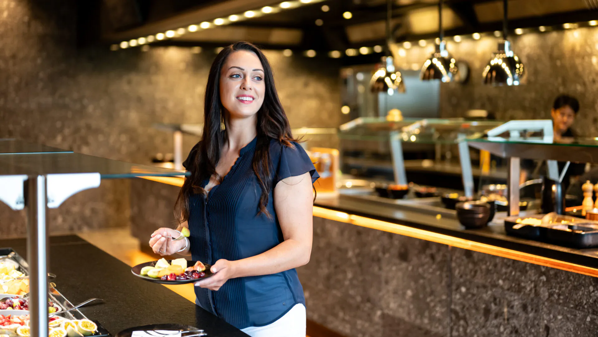 Frau am Buffet mit Teller voller Obst