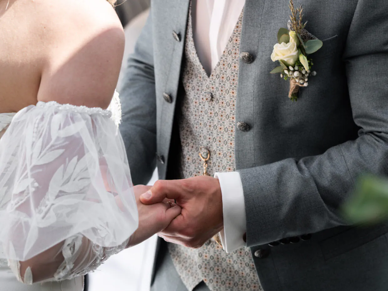 Hände eines Hochzeitspaares, elegantes Hochzeitsoutfit